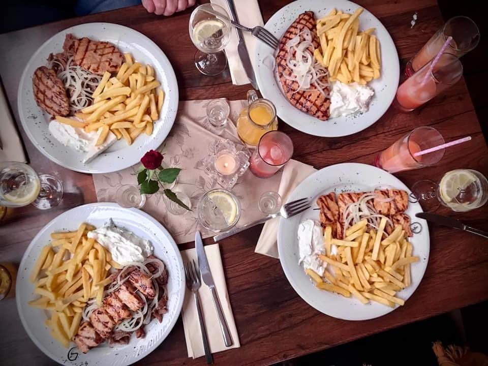 Gedeckter Tisch bei Tolis mit vier Tellern Gyros und Pommes, Getränken und Kerze