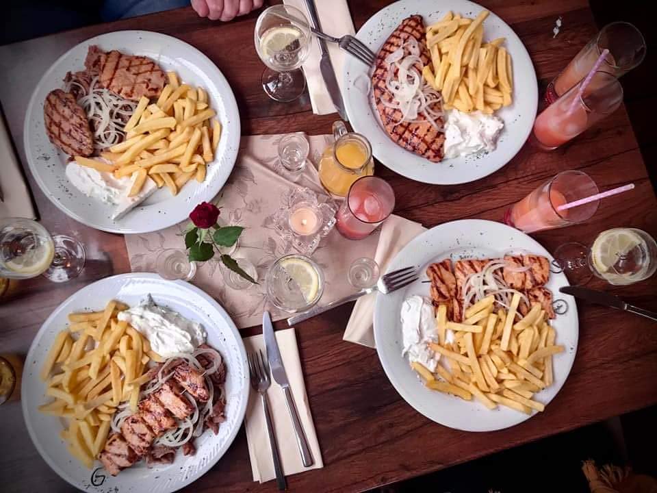 Gedeckter Tisch mit Grillgerichten und Getränken bei Tolis